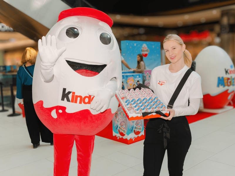 Hostess a Kinder kabalafigurájával egy bevásárlóközponti promóciós standnál